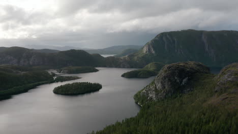 Scenic aerial footage gliding across fjord with forested islets and towering rock formations