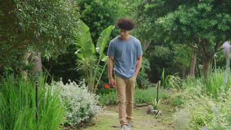 Happy-biracial-man-walking-in-garden-on-sunny-day