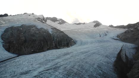 Aerial-fight-over-of-the-Gauli-glacier-in-the-Bernese-Oberland-region-of-the-Swiss-Alps-with-view-of-the-glacial-ice-at-sunset