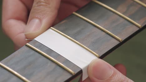 covering the guitar fingerboard with masking tape before polishing the frets - close up