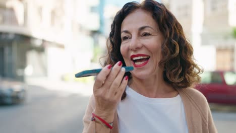 mujer de mediana edad sonriendo confiada hablando en el teléfono inteligente en la calle