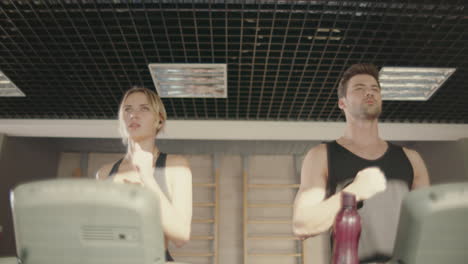 Sport-couple-training-run-on-treadmill-machine-in-fitness-club.