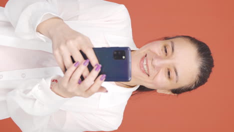 Video-Vertical-De-Una-Mujer-Feliz-Enviando-Mensajes-De-Texto-Por-Teléfono.-Sonriente.