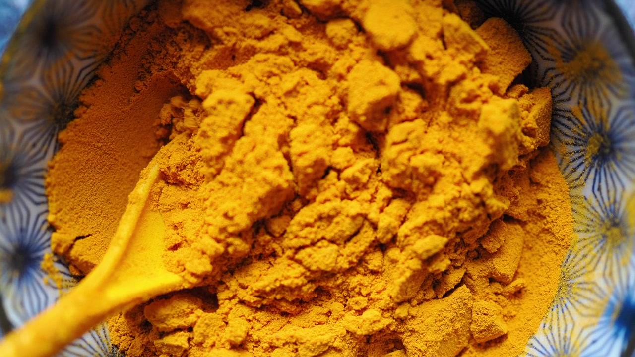 Yellow Turmeric Powder Being Scooped from a Bowl