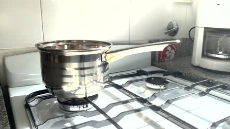 water boils in a pot on a gas stove, daytime sunlight