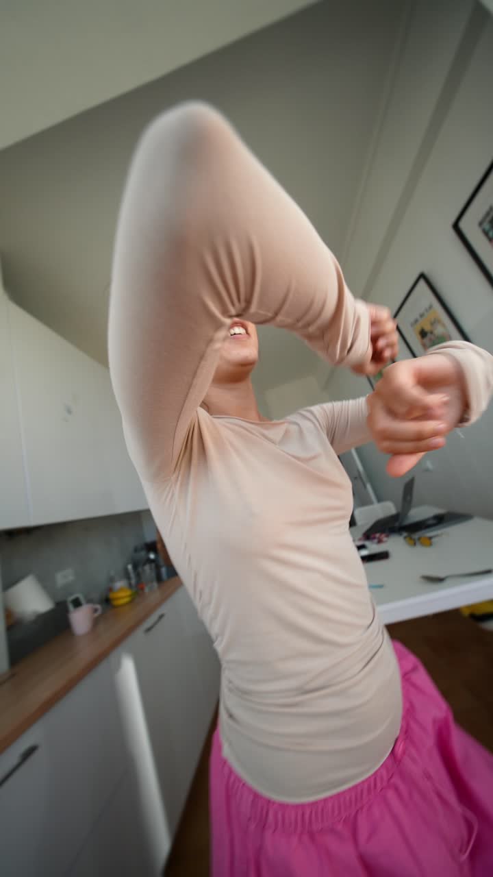 Jovem mulher enérgica dançando feliz em sua cozinha.