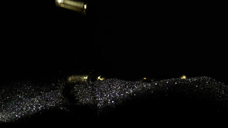 slow motion shot of falling 9mm parabellum bullets on black sand in studio,close up