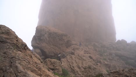 grupo de senderismo ascendiendo al roque nublo duroing una mañana brumosa en la isla de gran canaria, españa