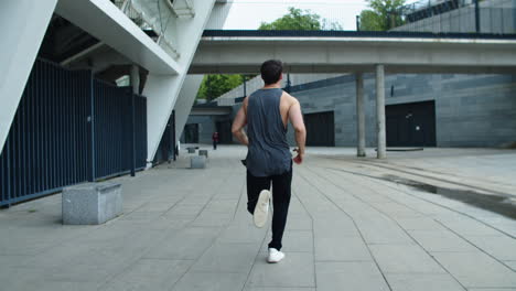 back view of sporty man running on urban street. athlete man jogging outdoor.