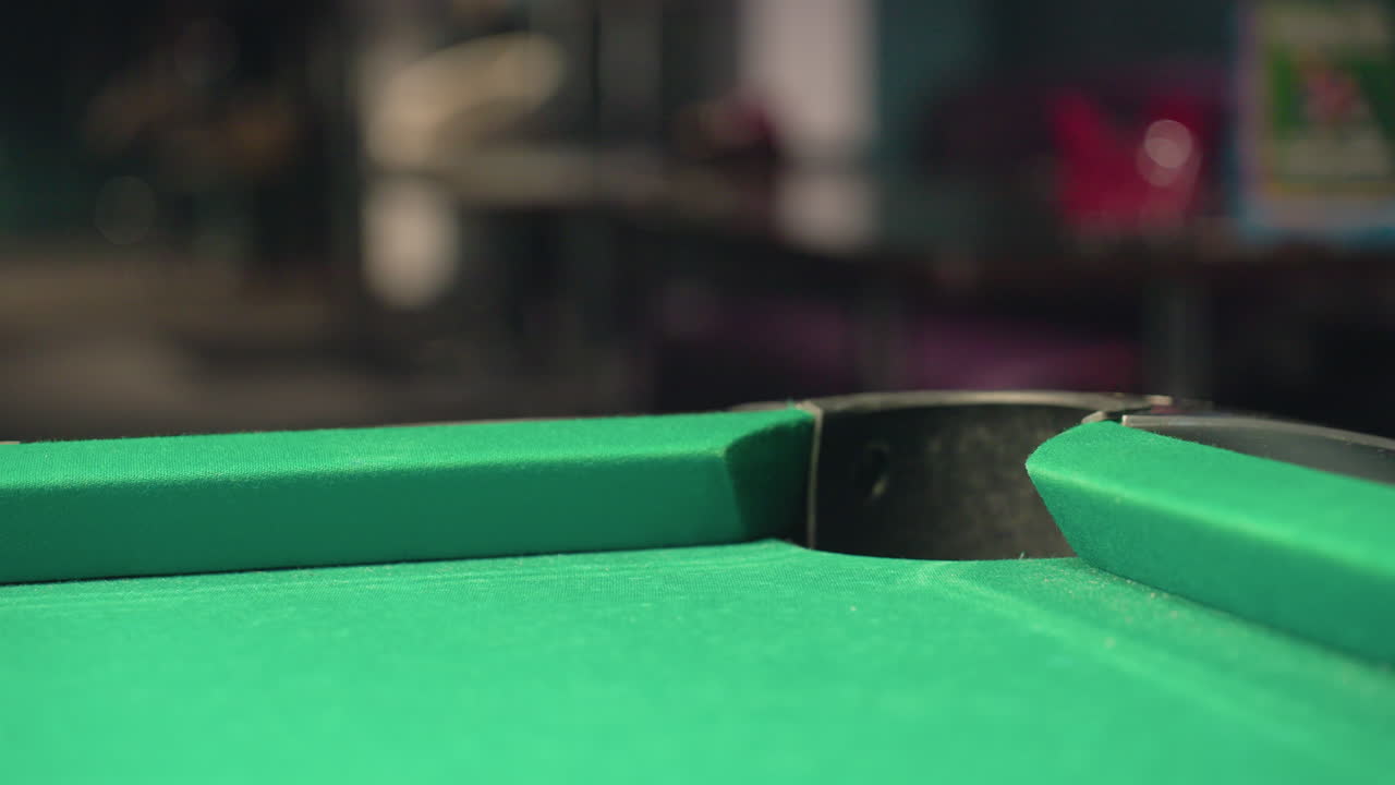 Close-up back shot of red billiard ball rolling rapidly into pool table pocket on green surface. Motion blur captures speed, precision, and excitement of shot, emphasizing accuracy, gameplay intensity