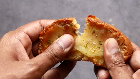 holding garlic bread against black background ,