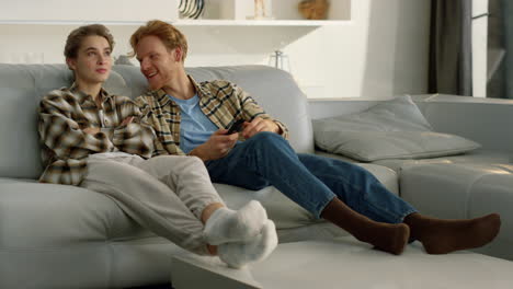 dos amigos disfrutando de un programa de televisión en casa. una pareja feliz mira comedia juntos