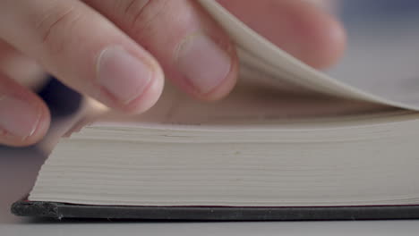 un hombre pasa con los dedos las páginas de un libro