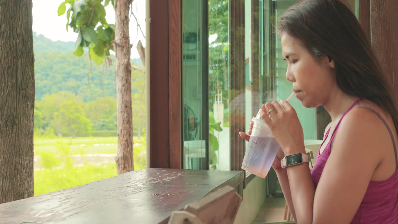 Side View Close Up Shot of a Thai Woman Drinking a Soda Drink at a Garden Caf&eacute; in Khao Yai, Thailand