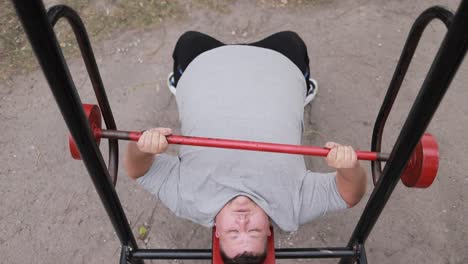 closeup of a fat man lifting a barbell lying down while exercising sports and motivation closeup of a fat man lifting a barbell lying down while exercising sports and motivation