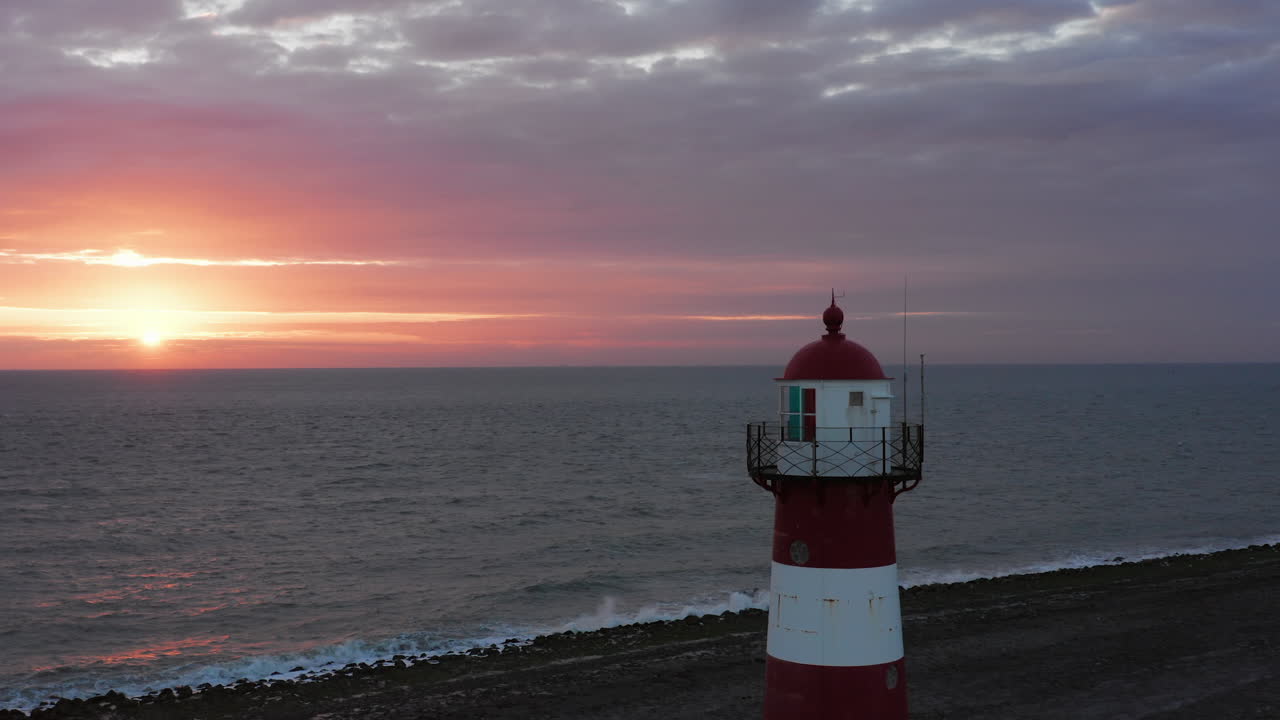 The lighthouse of Westkapelle during a bright orange sunset, with a lot of wind