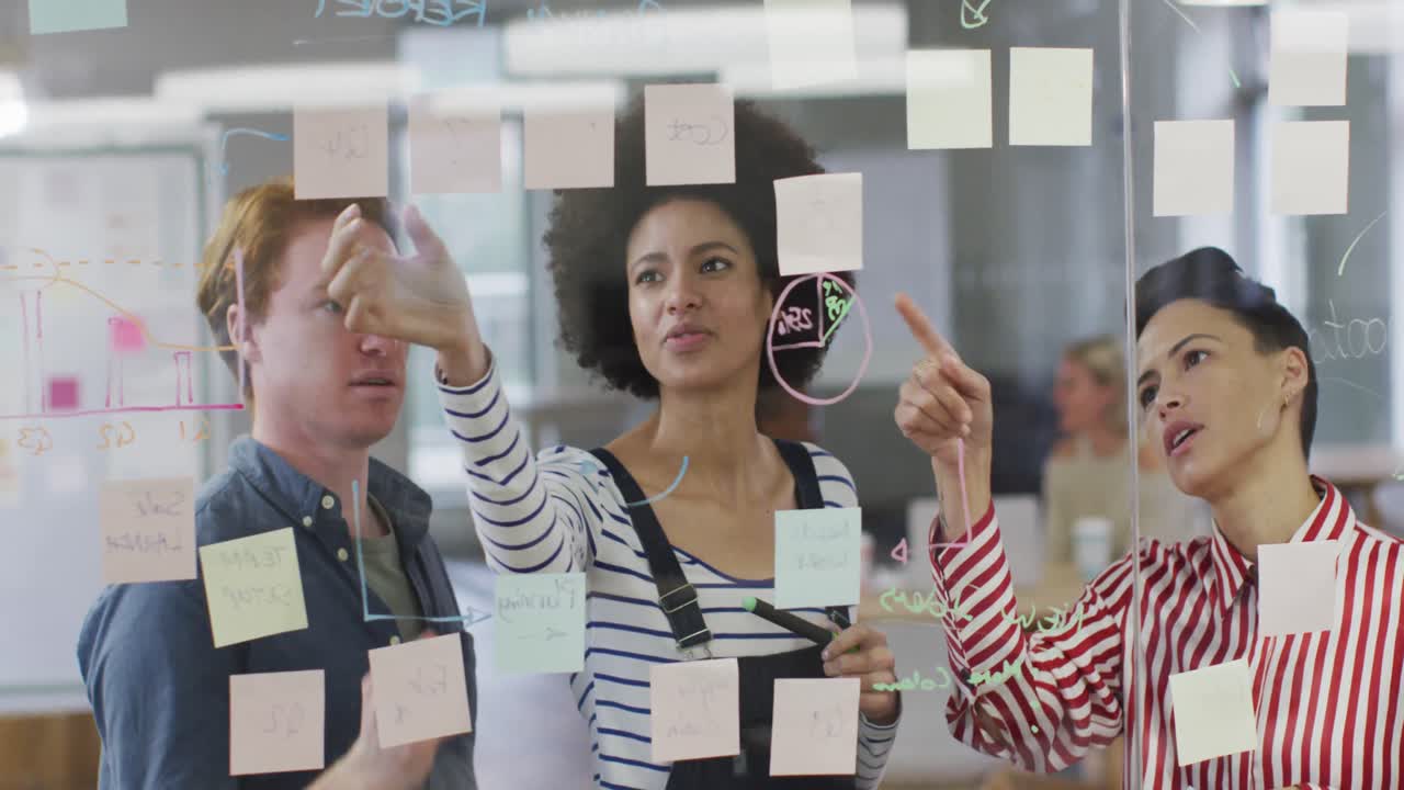 diversos colegas de negocios masculinos y femeninos discutiendo por una pared de vidrio con notas de memoria