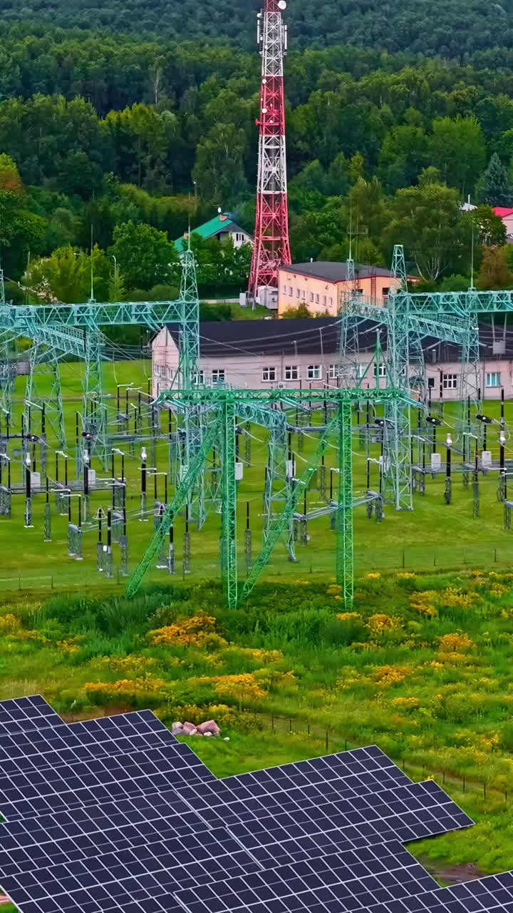 Solar power panels set on edge of transformer power grid lines, aerial of renewable energy use in farming zone, vertical