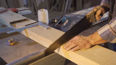 Close-up-carpenter-is-cutting-wood-with-a-handsaw.