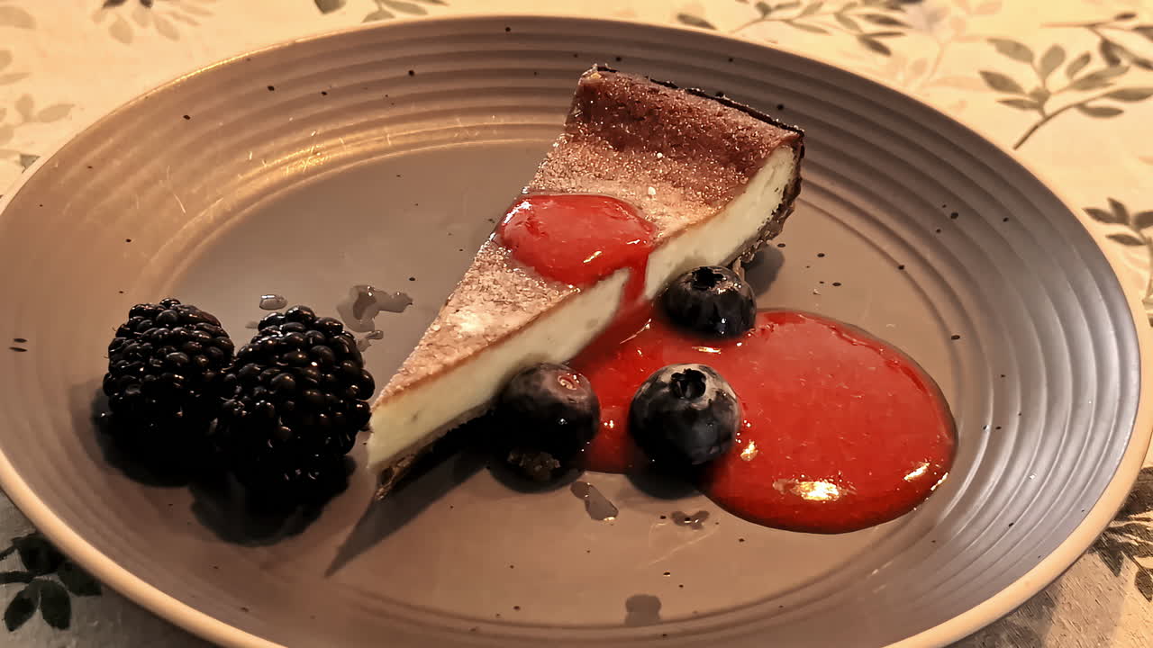 A beautifully presented piece of cake with fruits on a plate, elegantly served in a restaurant.