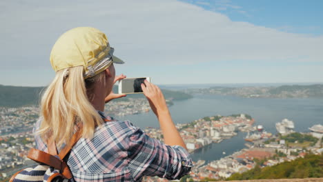 woman photographing a beautiful view of the city of bergen in norway tourism in scandinavia concept