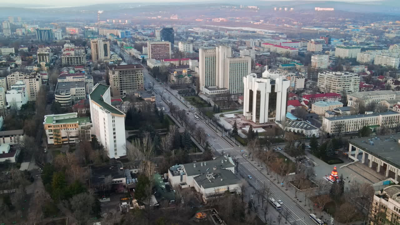 Aerial drone view of Chisinau. Panorama view of the Presidency and Parliament, multiple buildings in city center, roads with moving cars, bare trees. Moldova