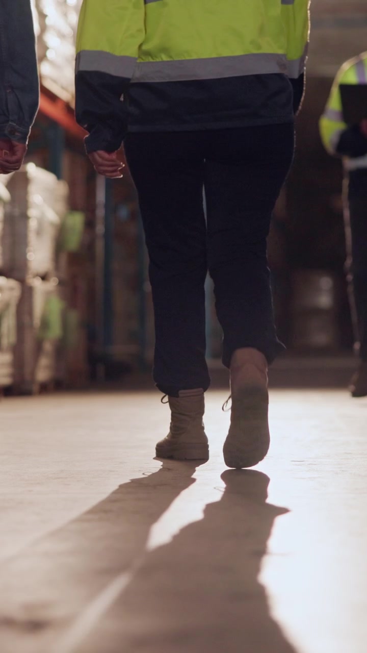 Warehouse Workers Walking Through Distribution Center Aisle