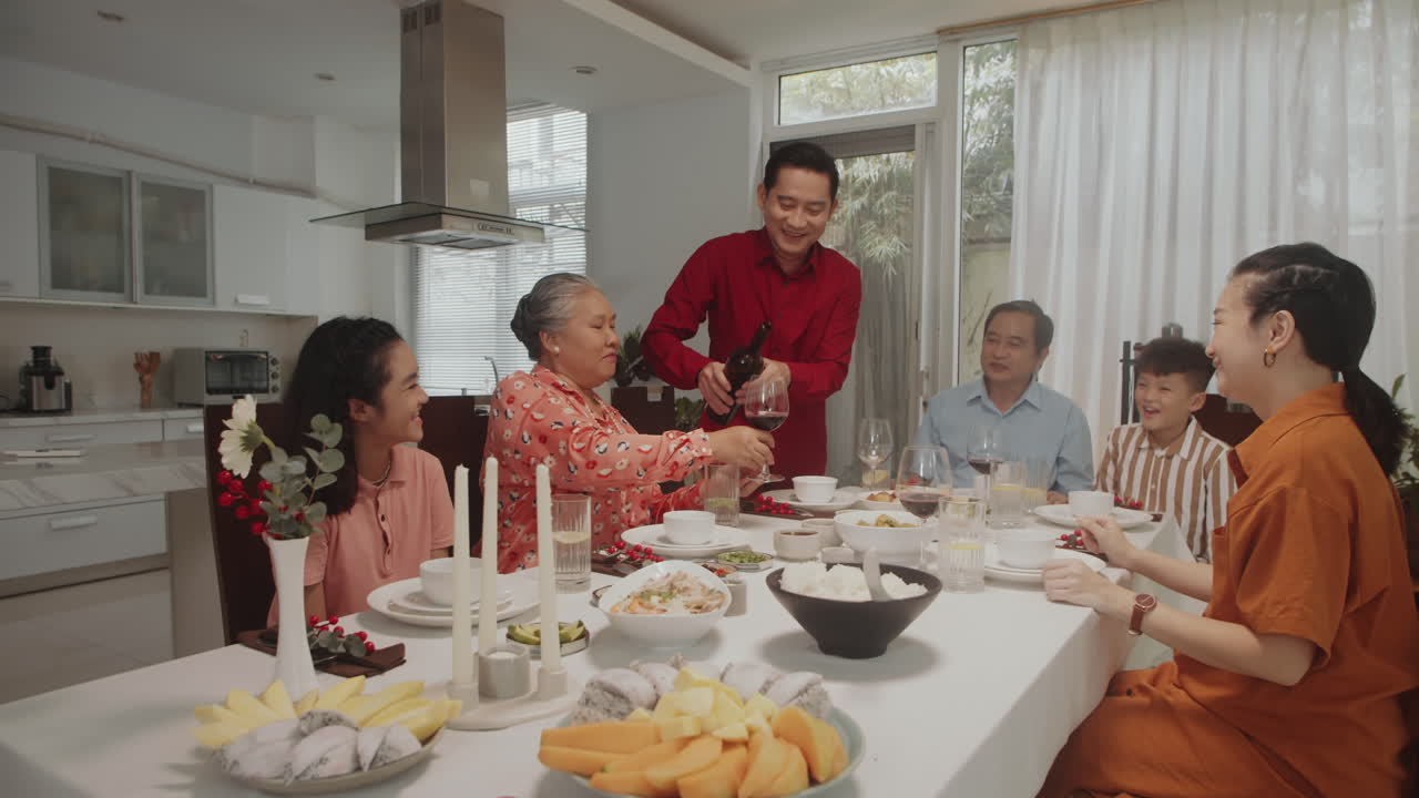 Man Pouring Wine in Glasses at Family Dinner