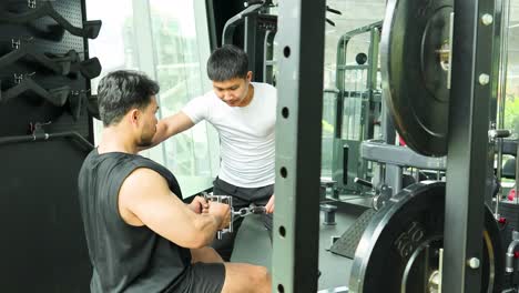 two men engage in a gym workout using a cable machine, focusing on strength training in a well-lit fitness environment