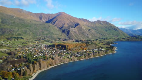 aerial backwards drone shot of the high mountain range at wanaka lake in autumn