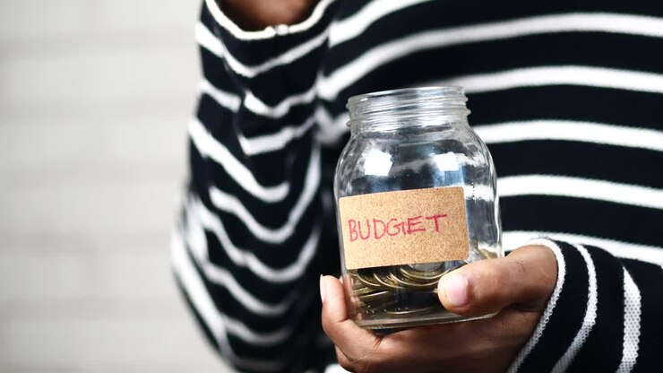 Budget text on a saving coins jar on white ,