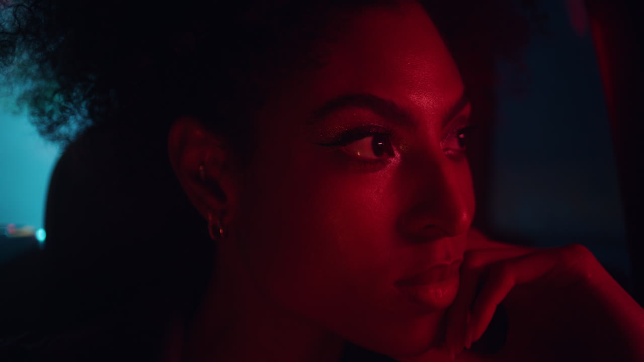Portrait curly-haired model posing dark car illuminated urban lights closeup