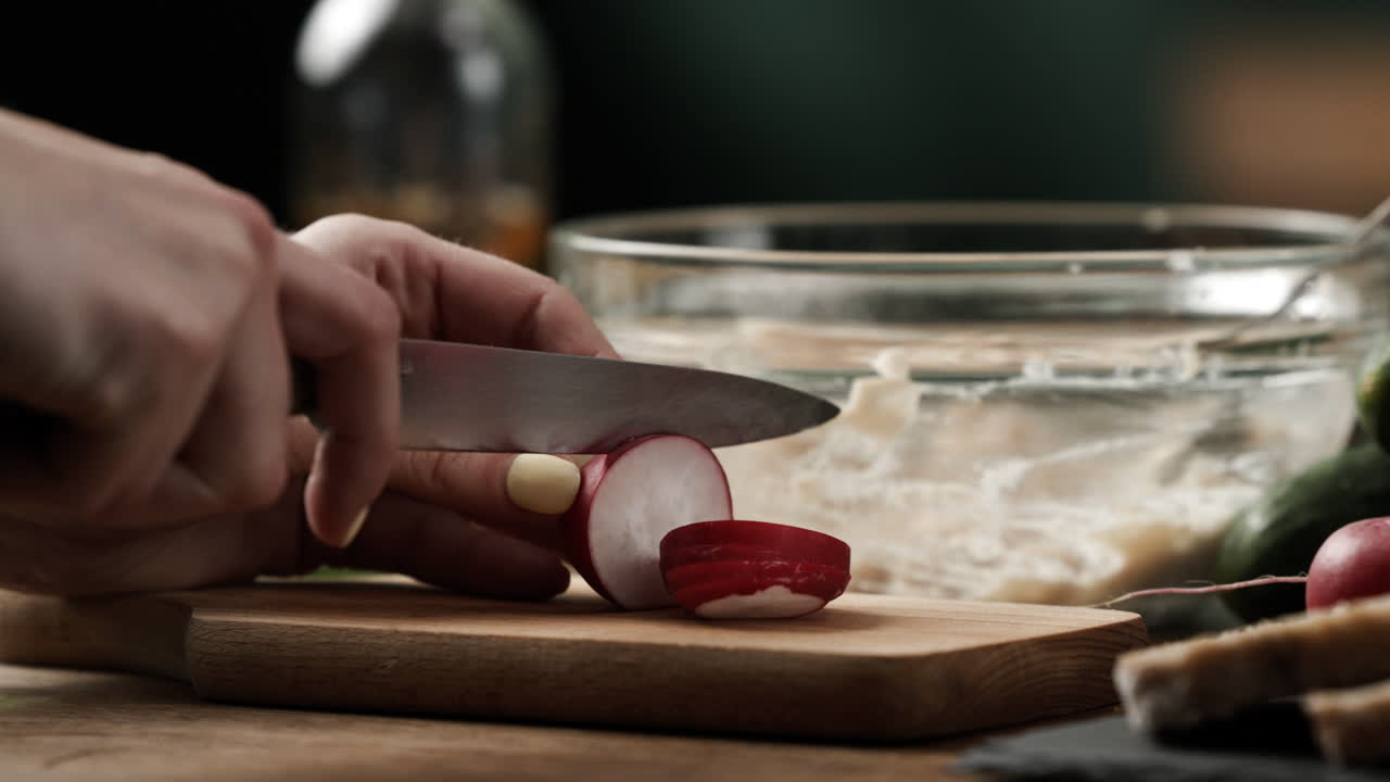Close up of slicing and cutting radish into small pieces to prepare healthy vegetable sandwich spread on colorful wooden kitchen table, 4k, 50fps