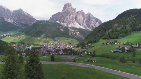 cyclist on a mountain road in the dolomites, italy, with a small town in the background, from a drone