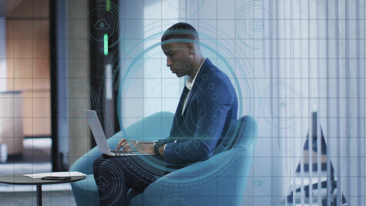Businessman typing on laptop in blue lounge chair activating cybersecurity graphics around laptop