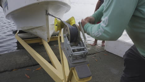 close-up shot of a man reeling a boat onto a small trailer ready to go home