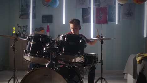 teen drummer rehearsing in bedroom teenager in casual clothes sitting near bed and playing drums during rehearsal in illuminated bedroom at home