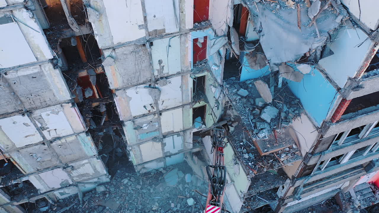Heavy machinery dismantling the old building. Excavator disassembling the ruins of the construction. View from above.