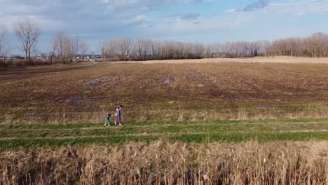 two adorable kids walking gently on the grassy trail at the meadow in monroe, michigan on a bright weather - wide shot