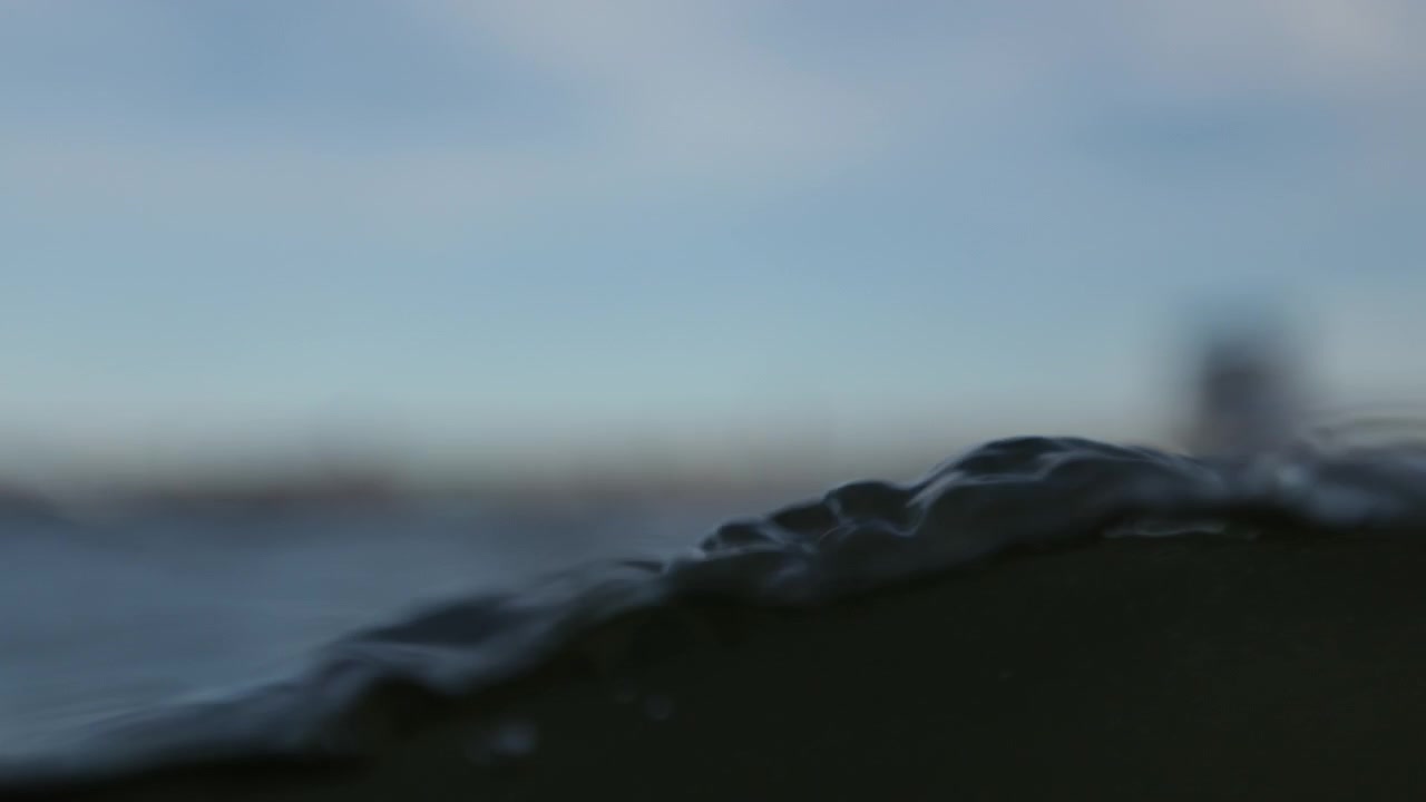 Punto di vista che affonda lentamente nell'acqua scura, onde e increspature mentre l'acqua si riversa, al rallentatore