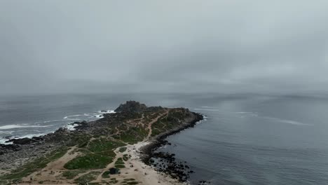 cinematic 4k drone clip over a wild rock formation peninsula on a cloudy rainy day in