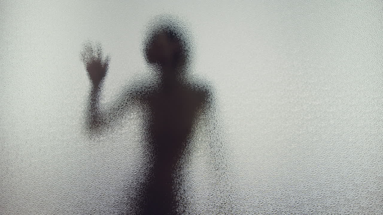 A female silhouette behind the frosted window touches the glass slowly