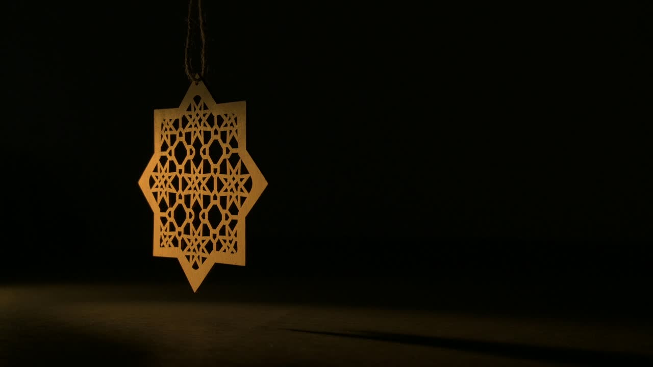 Decorazione islamica a forma di stella in legno che oscilla nell'oscurità con una luce soffusa durante il Ramadan