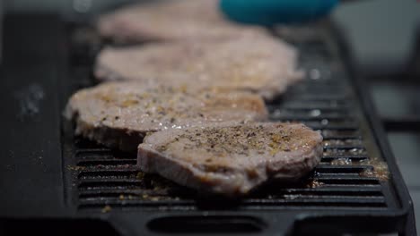 Close-up-of-steaks-smoking-on-grill