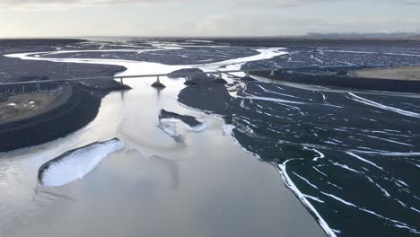 aerial panning shot of sula glacial river delta with bridge during sunny day in iceland