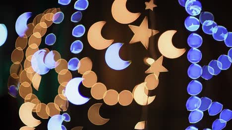 decorative moon and star lights softly glimmering against dark background, creating enchanting nighttime atmosphere with golden and blue glowing elements representing ramadan festivity