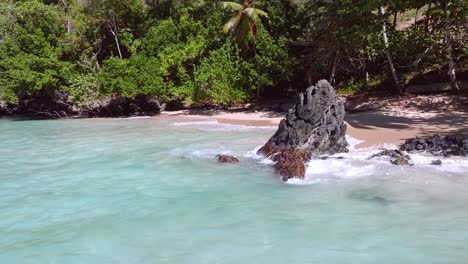 rocky stones, boulders on tropical sand beach, turquoise waves breaking