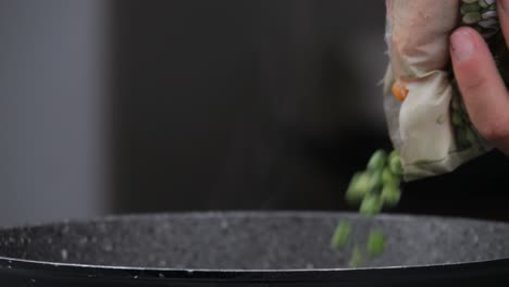 vaciando una bolsa de guisantes y zanahorias en la sartén
