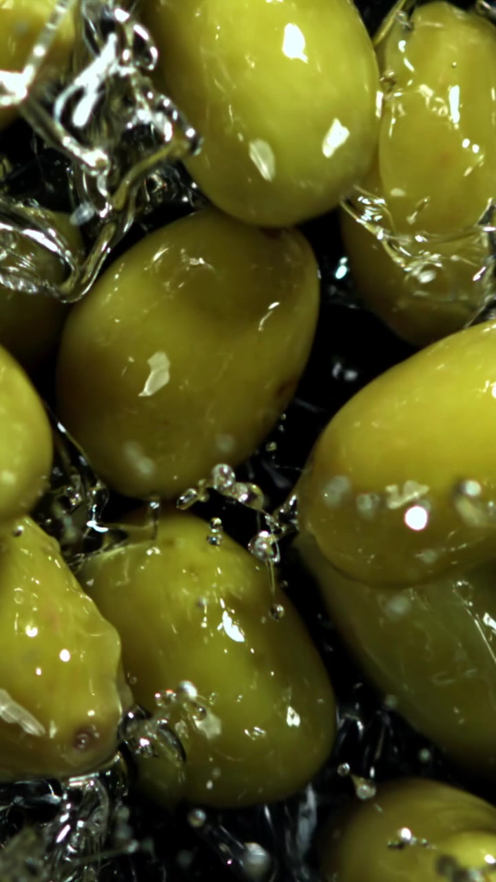Primo piano al rallentatore di olive verdi che schizzano nell'acqua