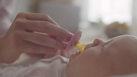 mother giving pacifier to baby